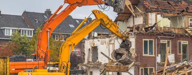 Two Demolition cranes demolishing old row of houses in the Netherlands